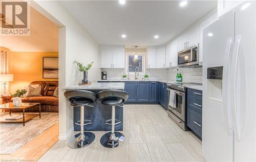 Kitchen featuring an island breakfast bar, upper white and lower blue cabinetry. - 6 Fran Ellen Crescent, Kitchener, ON - Indoor Photo Showing Kitchen With Upgraded Kitchen