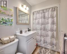 Full bathroom with hardwood / wood-style floors, shower / bath combo, toilet, and vanity - 