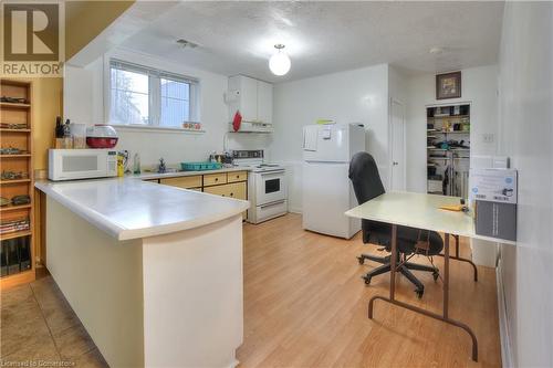 Kitchen featuring white appliances, white cabinets, a textured ceiling, light hardwood / wood-style floors, and kitchen peninsula - 524 Krug Street, Kitchener, ON - Indoor