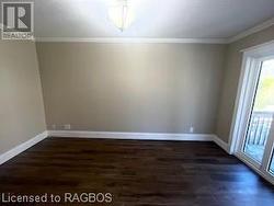 Spare room featuring dark wood-type flooring and ornamental molding - 