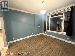 Spare room featuring ornamental molding and dark wood-type flooring - 