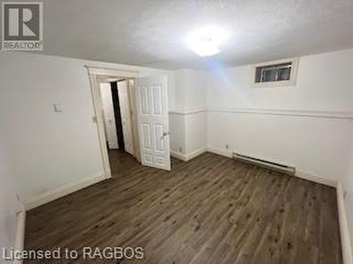 Basement with a textured ceiling, baseboard heating, and dark wood-type flooring - 745 4Th Avenue East Avenue, Owen Sound, ON 