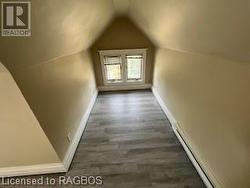 Bonus room with a baseboard radiator, dark wood-type flooring, and vaulted ceiling - 