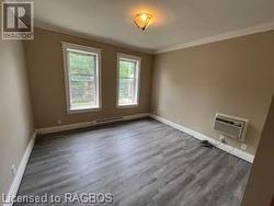 Empty room with a wall mounted air conditioner, dark hardwood / wood-style floors, and ornamental molding - 