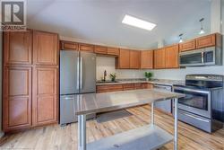 Kitchen featuring appliances with stainless steel finishes, light wood-type flooring, lofted ceiling, and sink - 