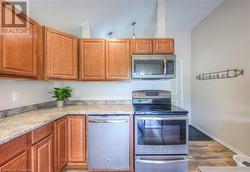 Kitchen with stainless steel appliances, light stone counters, and light hardwood / wood-style floors - 