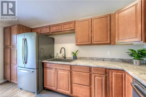 Kitchen featuring stainless steel fridge, sink, light stone counters, and light wood-type flooring - 8 Gerrard Avenue, Cambridge, ON - Indoor Photo Showing Kitchen