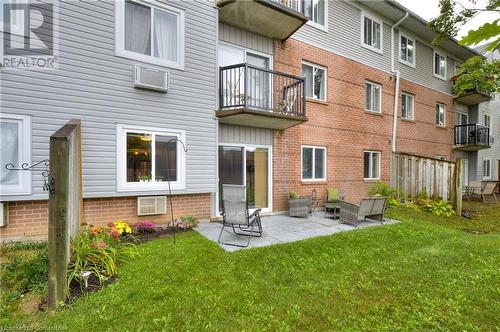 Rear view of house featuring a wall mounted air conditioner, a yard, and a patio - 276 Eiwo Court Unit# 105, Waterloo, ON - Outdoor With Exterior