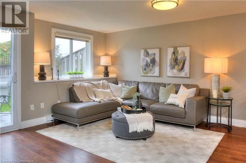 Living room featuring a baseboard heating unit and hardwood / wood-style flooring - 276 Eiwo Court Unit# 105, Waterloo, ON - Indoor Photo Showing Living Room