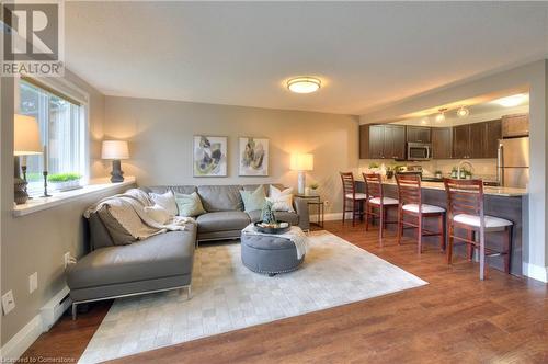 Living room with hardwood / wood-style floors and a baseboard heating unit - 276 Eiwo Court Unit# 105, Waterloo, ON - Indoor Photo Showing Living Room