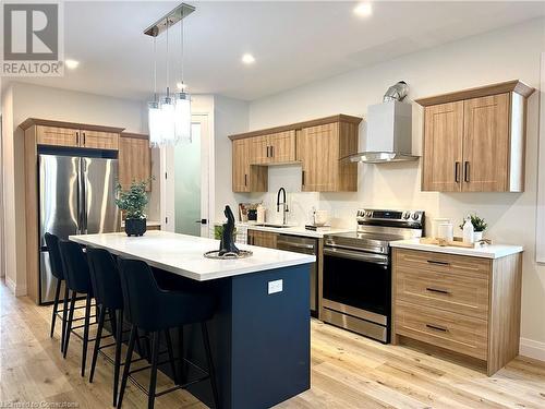 Kitchen with wall chimney exhaust hood, a kitchen island, light hardwood / wood-style floors, and appliances with stainless steel finishes - 53 Giles Street, London, ON - Indoor Photo Showing Kitchen With Stainless Steel Kitchen