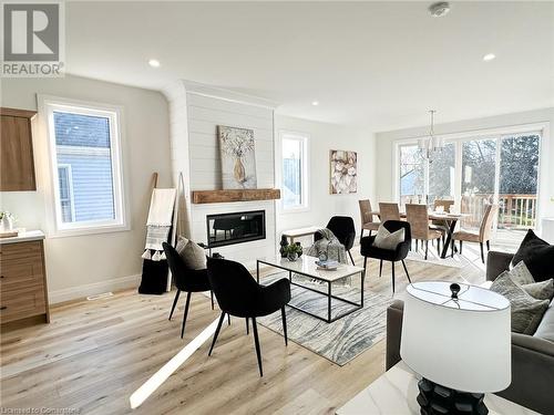 Living room featuring a fireplace, light wood-type flooring, and an inviting chandelier - 53 Giles Street, London, ON - Indoor With Fireplace