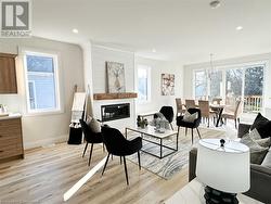 Living room featuring a fireplace, light wood-type flooring, and an inviting chandelier - 