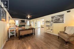 Living room featuring hardwood / wood-style floors, ceiling fan, and a stone fireplace - 