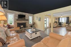 Living room featuring plenty of natural light, ceiling fan, dark hardwood / wood-style flooring, and a fireplace - 