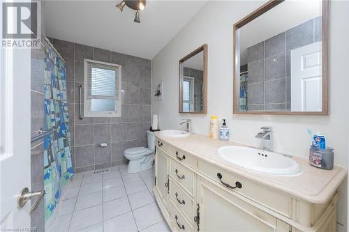 Bathroom featuring curtained shower, tile patterned floors, toilet, vanity, and tile walls - 9202 9Th Line, Halton Hills, ON - Indoor Photo Showing Bathroom