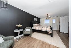 Bedroom featuring lofted ceiling, hardwood / wood-style flooring, and a notable chandelier - 