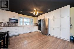 Kitchen with tasteful backsplash, white cabinetry, and appliances with stainless steel finishes - 