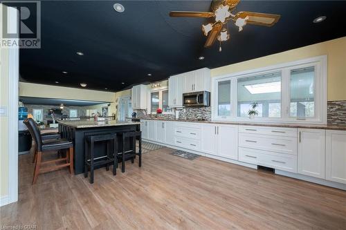 Kitchen with white cabinets, a center island, light stone countertops, and a breakfast bar area - 9202 9Th Line, Halton Hills, ON - Indoor Photo Showing Kitchen