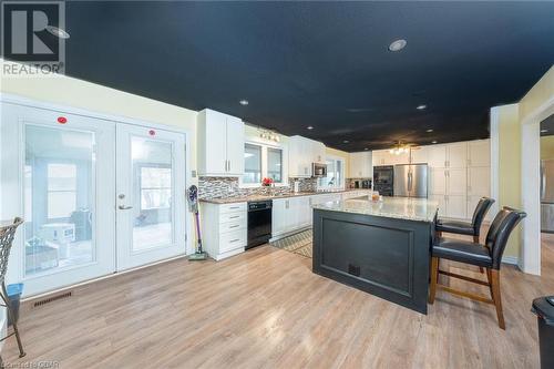 Kitchen featuring light wood-type flooring, white cabinetry, appliances with stainless steel finishes, and french doors - 9202 9Th Line, Halton Hills, ON - Indoor Photo Showing Kitchen With Upgraded Kitchen