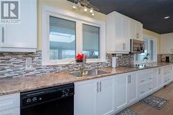 Kitchen featuring black appliances, white cabinets, sink, and a wealth of natural light - 