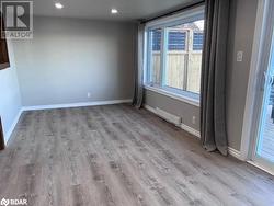 Empty room with light wood-type flooring and a baseboard heating unit - 