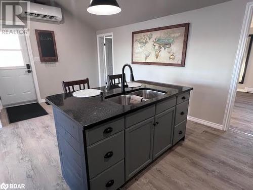 Kitchen with a wall mounted AC, a kitchen island with sink, sink, and light wood-type flooring - 80 Ridley Street, Prince Edward County, ON - Indoor Photo Showing Kitchen With Double Sink