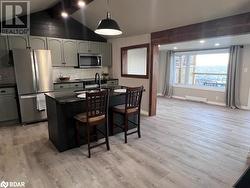 Kitchen featuring hanging light fixtures, stainless steel appliances, lofted ceiling, and light hardwood / wood-style flooring - 