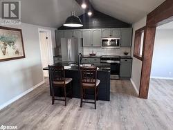 Kitchen featuring appliances with stainless steel finishes, tasteful backsplash, vaulted ceiling, sink, and hanging light fixtures - 