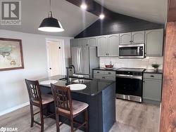 Kitchen with pendant lighting, light wood-type flooring, stainless steel appliances, and sink - 