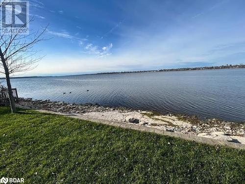 Unfurnished room featuring hardwood / wood-style floors, a water view, and a baseboard heating unit - 80 Ridley Street, Prince Edward County, ON - Outdoor With Body Of Water With View