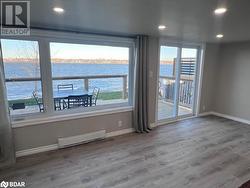 Unfurnished room featuring hardwood / wood-style floors, a water view, and a baseboard heating unit - 