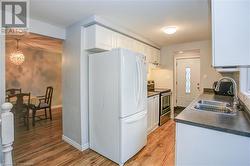 Kitchen featuring stainless steel range with electric stovetop, white cabinets, white refrigerator, sink, and light hardwood / wood-style floors - 