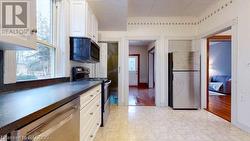 Kitchen with white cabinets, appliances with stainless steel finishes, and light hardwood / wood-style flooring - 