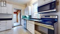 Kitchen with white cabinets, stainless steel appliances, and wooden ceiling - 