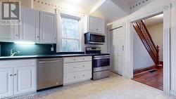 Kitchen featuring sink, stainless steel appliances, white cabinetry, and light hardwood / wood-style flooring - 