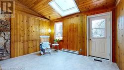 Living area featuring a wealth of natural light, a baseboard heating unit, and wood walls - 