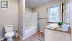 Full bathroom featuring toilet, vanity, shower / tub combo, and hardwood / wood-style flooring - 