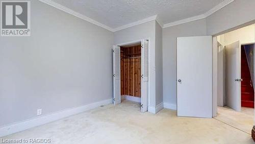 Unfurnished bedroom with lofted ceiling, ornamental molding, a textured ceiling, light colored carpet, and a closet - 550 10Th Street A West, Owen Sound, ON - Indoor