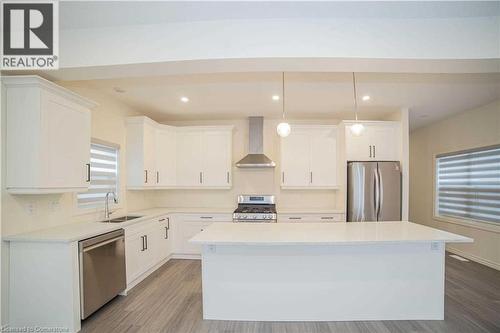 Kitchen with a center island, sink, wall chimney exhaust hood, decorative light fixtures, and stainless steel appliances - 182 Byers Street, London, ON - Indoor Photo Showing Kitchen With Double Sink With Upgraded Kitchen