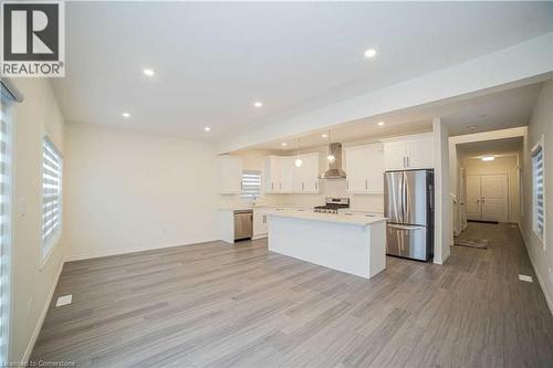 Kitchen with appliances with stainless steel finishes, light hardwood / wood-style floors, and wall chimney exhaust hood - 182 Byers Street, London, ON - Indoor Photo Showing Kitchen