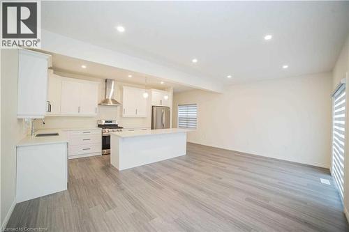 Kitchen with pendant lighting, a center island, light wood-type flooring, white cabinetry, and stainless steel appliances - 182 Byers Street, London, ON - Indoor Photo Showing Kitchen