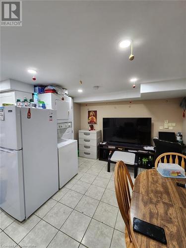 Kitchen with white fridge, white cabinetry, stacked washer and dryer, and light tile patterned floors - 744-746 Queen Street S, Kitchener, ON - Indoor