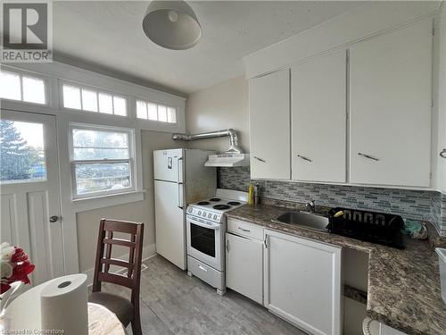 Kitchen featuring backsplash, wall chimney exhaust hood, white appliances, sink, and white cabinets - 744-746 Queen Street S, Kitchener, ON - Indoor Photo Showing Kitchen