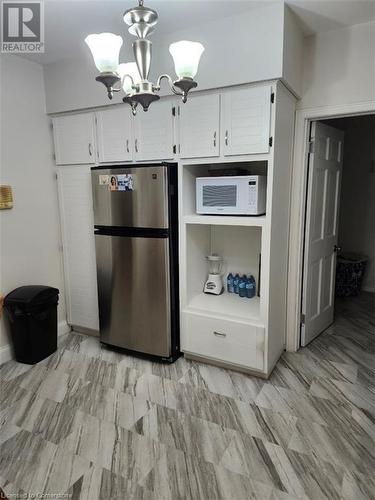 Kitchen with white cabinetry, stainless steel refrigerator, and a chandelier - 744-746 Queen Street S, Kitchener, ON - Indoor