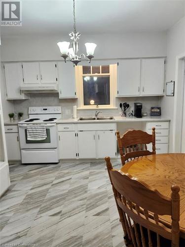 Kitchen with electric range, sink, hanging light fixtures, a chandelier, and white cabinets - 744-746 Queen Street S, Kitchener, ON - Indoor Photo Showing Kitchen With Double Sink