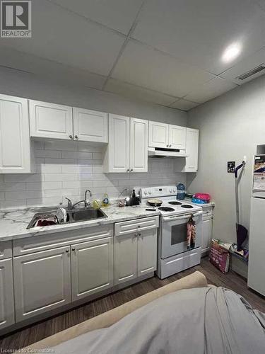 Kitchen featuring sink, dark hardwood / wood-style flooring, white appliances, decorative backsplash, and white cabinets - 744-746 Queen Street S, Kitchener, ON - Indoor Photo Showing Kitchen With Double Sink