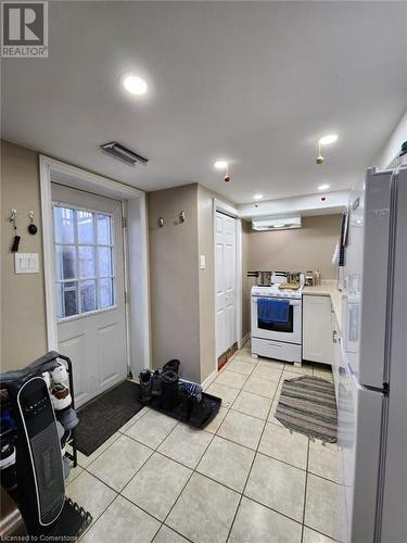 Kitchen with light tile patterned floors, white cabinets, exhaust hood, and white appliances - 744-746 Queen Street S, Kitchener, ON - Indoor