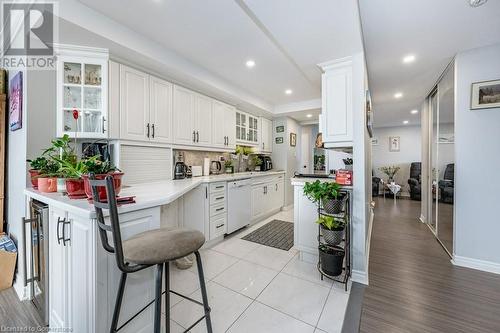 Kitchen with white dishwasher, white cabinetry, light hardwood / wood-style flooring, and tasteful backsplash - 3100 Kirwin Avenue Unit# 2102, Mississauga, ON - Indoor