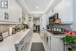 Kitchen with white cabinets, light tile patterned floors, white appliances, and sink - 